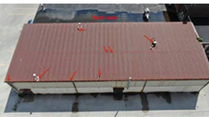 Before: aerial view of a rusting red metal roof on a commercial building with leak points marked in red