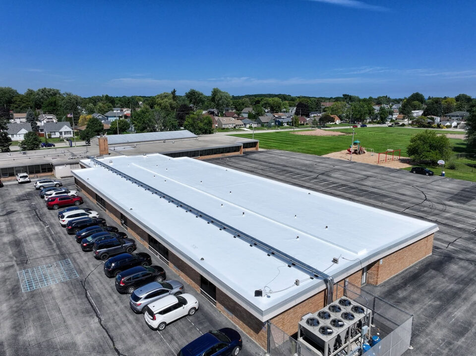 After: the same school flat roof finished bright white with a silicone roof coating system