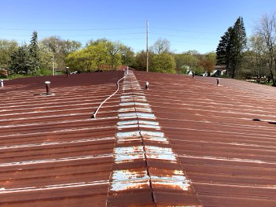 Before: rusted standing seam metal commercial roof in Illinois with worn seams and patched fasteners