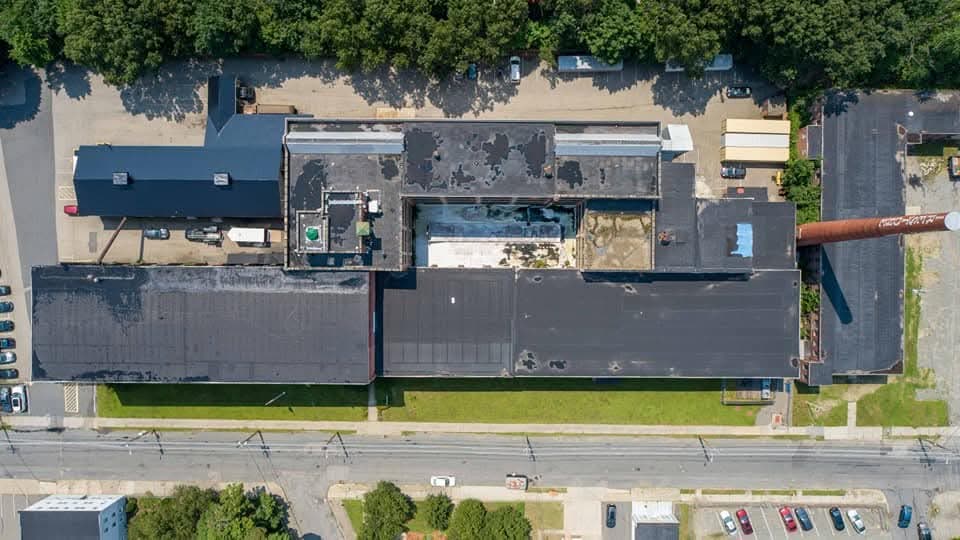 Before: aerial view of an aging black EPDM commercial roof in Spring Glen, Pennsylvania with patched seams and ponding stains