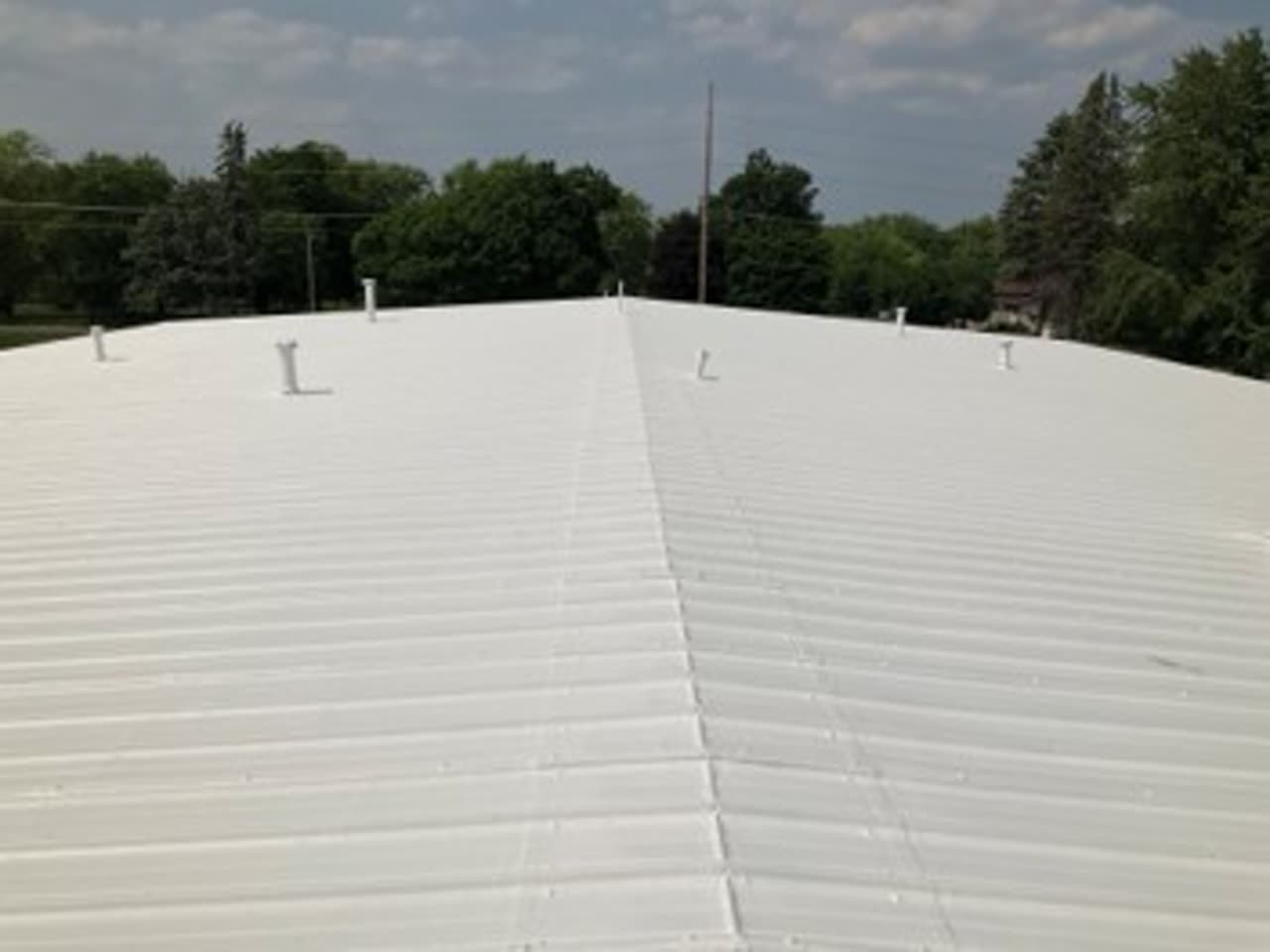 Rusted metal commercial roof in Peoria, Illinois restored with a Conklin white reflective roof coating