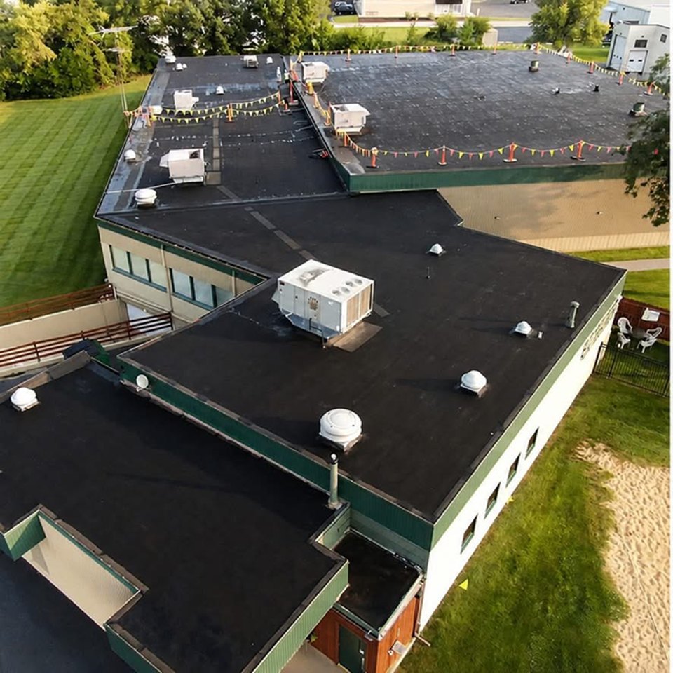 Before: aerial view of a bowling center's aging black EPDM flat roof with weathered seams and rooftop HVAC units