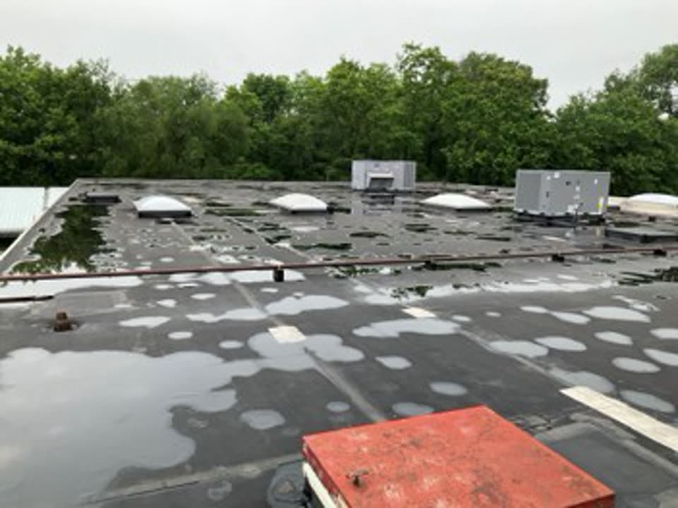 Before: aging black EPDM flat roof in Illinois with ponding water and weathered seams around skylights