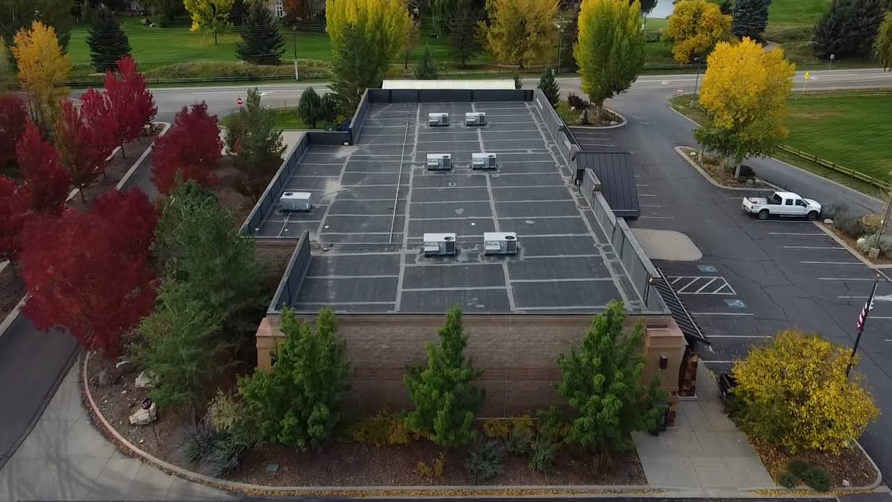 Before: aerial view of a retail hardware store's aging dark flat roof with weathered seams and rooftop HVAC units